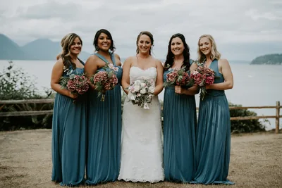 A bride and her bridesmaids holding bouquets, mountains behind them