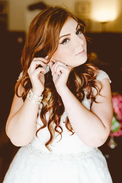 A bride putting on an earring