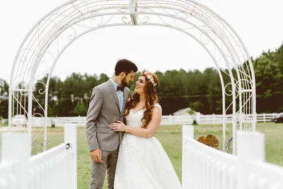 Bride and groom beneath a white garden arch