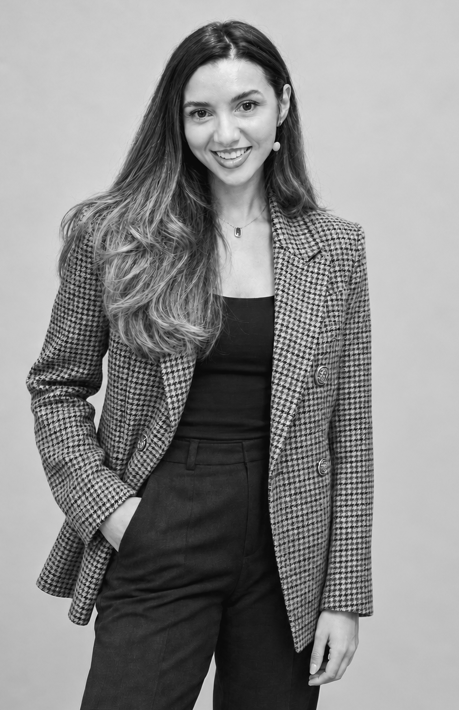 Black-and-white studio portrait of a photographer in a checked blazer